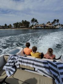 Three children enjoy a scenic boat ride, taking in the beautiful waterfront views — a perfect family outing on the water.