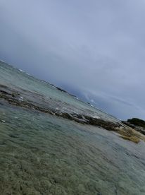 An unclear image of a coastal scene with water and rocks, lacking focus and identifiable features.