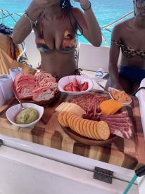 A vibrant spread of snacks and drinks on a boat, featuring charcuterie, fresh strawberries, and guacamole, perfect for enjoying a day on the water.