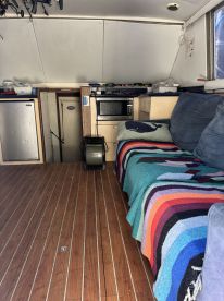 Interior view of a cozy boat cabin featuring comfortable seating and essential amenities, perfect for relaxing during a day on the water.