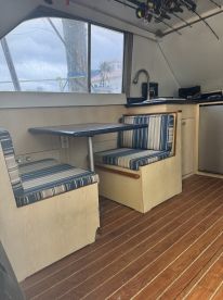Interior view of a cozy boat cabin featuring striped seating and a compact table, perfect for relaxing or dining while on the water.