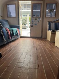 Interior view of a cozy boat cabin featuring a comfortable couch and wooden flooring, perfect for relaxing while on the water.