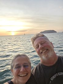 A joyful couple captures a selfie during a stunning sunset at sea, perfect for romantic moments and unforgettable memories on the water.
