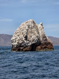 A stunning rock formation rises from the ocean, showcasing the natural beauty of the coastline — a perfect landmark for boating adventures.