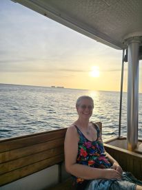 A woman enjoys a serene sunset on a boat, capturing a moment of relaxation and tranquility on the water.