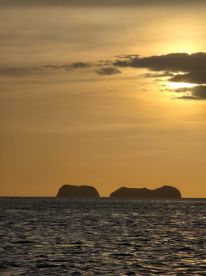 A stunning sunset view featuring silhouetted islands on the horizon, perfect for capturing the beauty of coastal destinations.