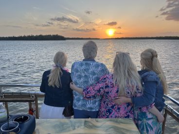 A group of friends enjoys a beautiful sunset from the deck of a boat, creating a memorable moment perfect for celebrations and gatherings on the water.