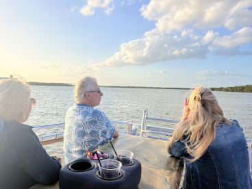A serene moment as a group enjoys drinks while watching the sunset from a boat, capturing the essence of relaxation on the water.
