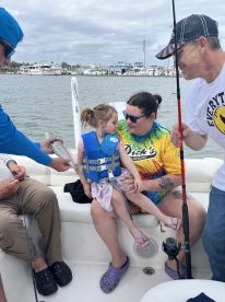 A joyful family moment on a boat as a child interacts with a fish caught during a fishing trip — a perfect blend of adventure and bonding on the water.