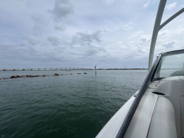 A scenic view from the side of a boat, showcasing the calm waters and a distant bridge, perfect for capturing the essence of a day on the water.