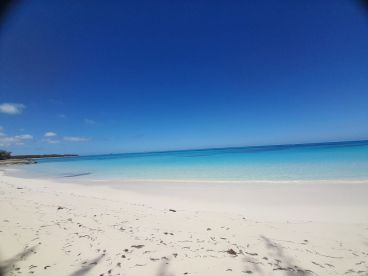 A stunning view of a pristine beach with soft white sand and crystal-clear turquoise waters, perfect for relaxing getaways and scenic boat trips.