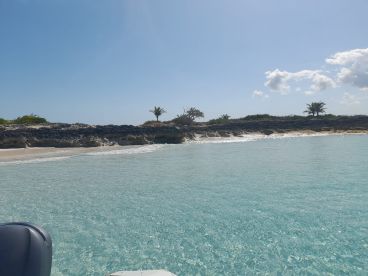 A serene view of a tranquil beach with clear turquoise waters and lush greenery, perfect for a relaxing getaway or island exploration.