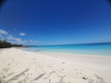 A stunning view of a pristine beach with soft white sand and crystal-clear turquoise waters, perfect for relaxation and scenic getaways.