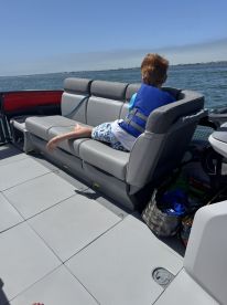 A young boy relaxes on the comfortable seating of a boat, enjoying the scenic views of the water — perfect for family outings and leisure time on the water.