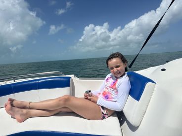 A cheerful child relaxes on the boat, enjoying a sunny day on the ocean — perfect for family outings and memorable adventures on the water.