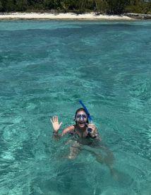 A joyful snorkeler waves from the crystal-clear waters, showcasing the vibrant marine life and stunning beach backdrop — a perfect moment for underwater adventures.