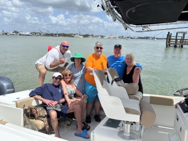 A cheerful group of friends poses for a fun photo on their boat, capturing the joy of a day out on the water.