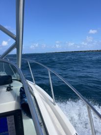 A view from the helm of a boat cruising through vibrant blue waters, showcasing the vessel's sleek design and the surrounding seascape.