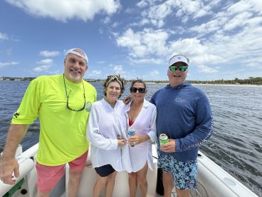 A cheerful group of friends enjoys a day on the water, holding drinks and soaking up the sun aboard their boat — perfect for a fun-filled outing.