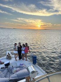 A group of friends poses on the deck of a boat during a stunning sunset, capturing the essence of a perfect boat party experience.