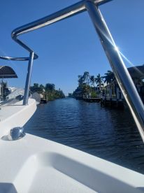 A scenic view from the bow of a boat, showcasing a tranquil waterway lined with palm trees — perfect for leisurely cruising.