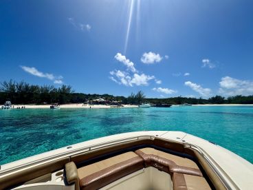 A stunning view from a boat overlooking a picturesque beach with turquoise waters and guests enjoying the sun — a perfect destination for relaxation and fun in the sun.