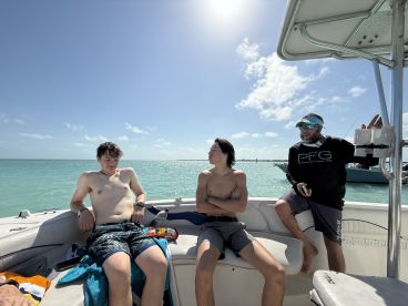 A group of friends relaxes on a boat under the sun, enjoying a beautiful day on the water — perfect for a fun outing or adventure.