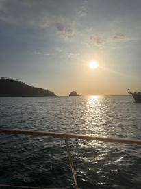 A serene sunset view from a boat, showcasing the tranquil waters and distant islands — perfect for evening cruises and relaxation on the water.