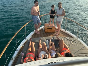 A lively group enjoys a sunny day on a yacht, with some sunbathing on the deck while others engage in conversation — perfect for family outings or celebrations on the water.
