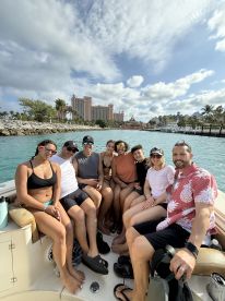 A lively group of friends enjoys a fun day on the water, capturing memories aboard a boat with a stunning backdrop of the Atlantis resort.