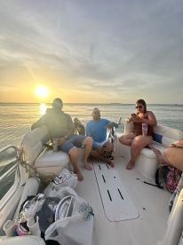 A group of friends enjoys a sunset cruise on a boat, capturing the perfect moment of relaxation and camaraderie on the water.