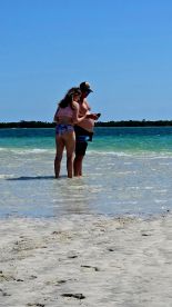 A couple shares a tender moment in shallow water at the beach, perfect for romantic getaways or special celebrations.