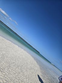 A picturesque view of a sandy beach with clear turquoise waters, perfect for a relaxing day by the coast.