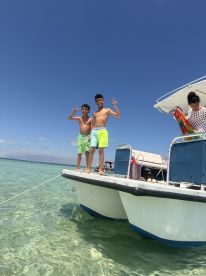 Two boys pose joyfully on the edge of a pontoon boat, enjoying a sunny day in clear waters — a perfect moment of fun and adventure on the water.
