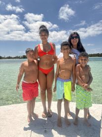 A joyful family poses together at the beach, enjoying a sunny day in the water — perfect for creating lasting memories during summer vacations.