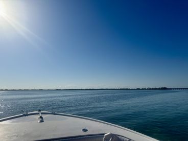 A serene view from the front of a boat, showcasing calm waters and a clear blue sky — perfect for a day of relaxation on the water.