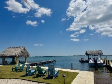 A scenic view of a waterfront area featuring a thatched roof structure and a docked boat, perfect for relaxing by the water.