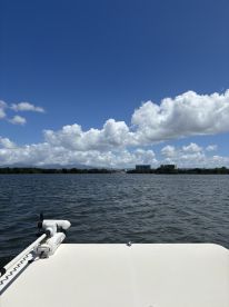 A serene view from the bow of a boat, showcasing the calm waters and fluffy clouds above, perfect for a relaxing day on the water.