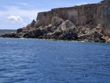 A stunning view of rocky cliffs rising above the clear blue waters, showcasing the natural beauty of the coastline.