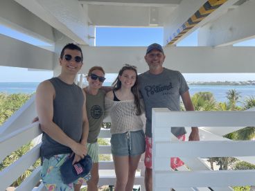 A cheerful family poses for a photo with a stunning ocean view in the background, capturing a memorable moment during their boating adventure.