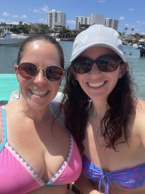 Two friends pose for a cheerful selfie by the water, enjoying a sunny day at the beach — perfect for capturing memorable moments during a fun outing.