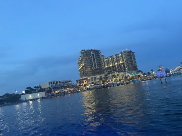 A picturesque view of a waterfront city at dusk, showcasing vibrant lights reflecting on the water — perfect for evening boat tours and scenic cruises.