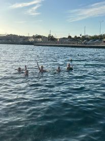 A lively group enjoys a refreshing swim in the water, capturing the joy of a perfect day out on the boat.
