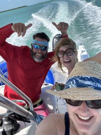 A joyful group enjoys a thrilling ride on a boat, celebrating with smiles and thumbs up against a backdrop of turquoise waters — perfect for adventure seekers.