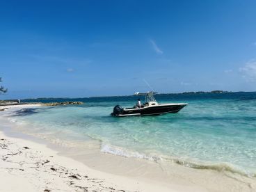 A sleek boat approaches a pristine beach, showcasing the beauty of tropical waters — perfect for island hopping adventures.