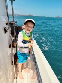 A cheerful child enjoys a sunny day on a boat, showcasing the joy of family adventures on the water.