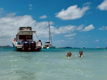 Two children enjoy a fun day of snorkeling in clear waters, with a boat anchored nearby, perfect for family adventures on the beach.