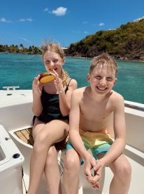 Two children enjoy a sunny day on a boat, showcasing smiles and a playful atmosphere — perfect for family adventures on the water.