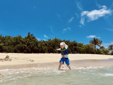 A joyful child splashes in the shallow waters of a sunny beach, capturing the essence of fun and adventure in a tropical paradise.