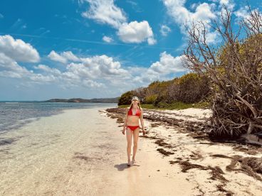 A woman strolls along a beautiful beach with clear waters and vibrant skies, capturing the essence of a perfect island getaway.
